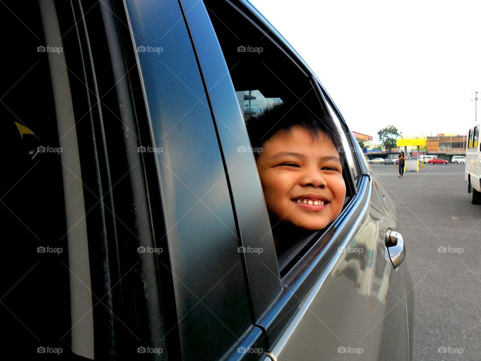 young boy peeking out a car window