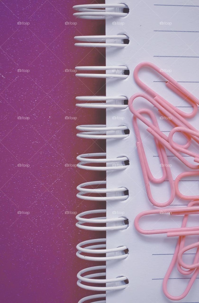 Paper clips and book in purple background...