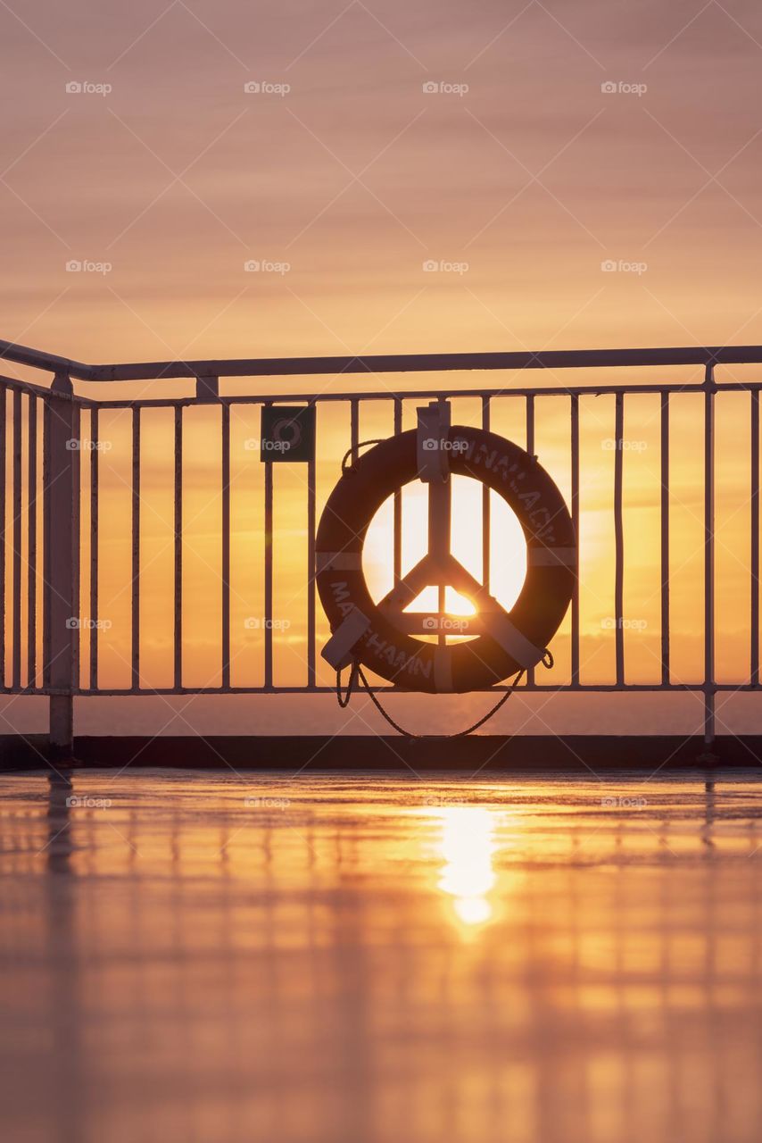 a lifebuoy hangs on the railing of a ferry against the backdrop of dawn in the Baltic Sea