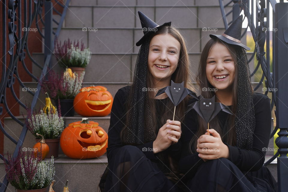 Two laughing teenage girls in Halloween witch costumes