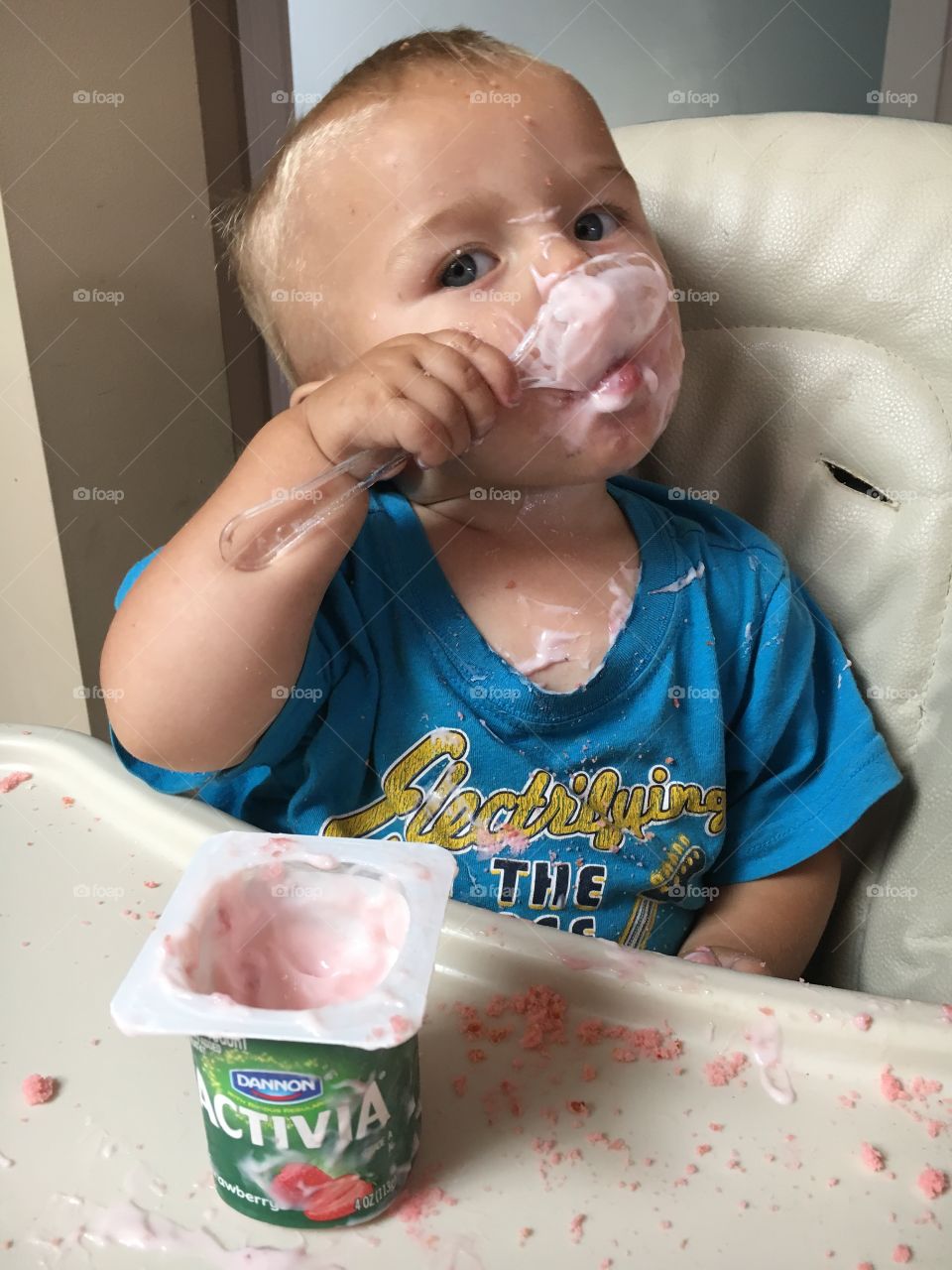 Cute baby eating Dannon Activia strawberry flavored yogurt 