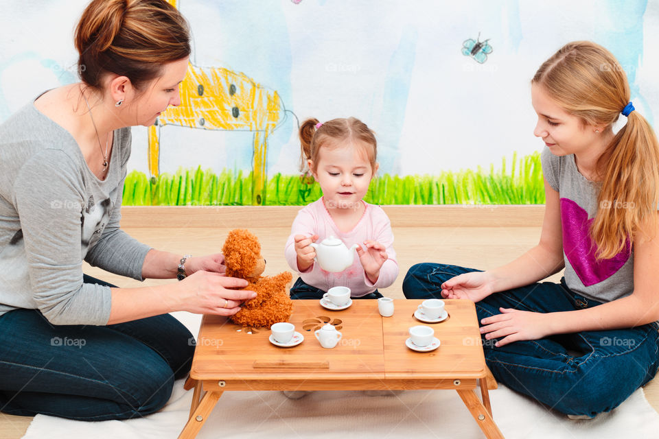 Little girl playing with mother and sister