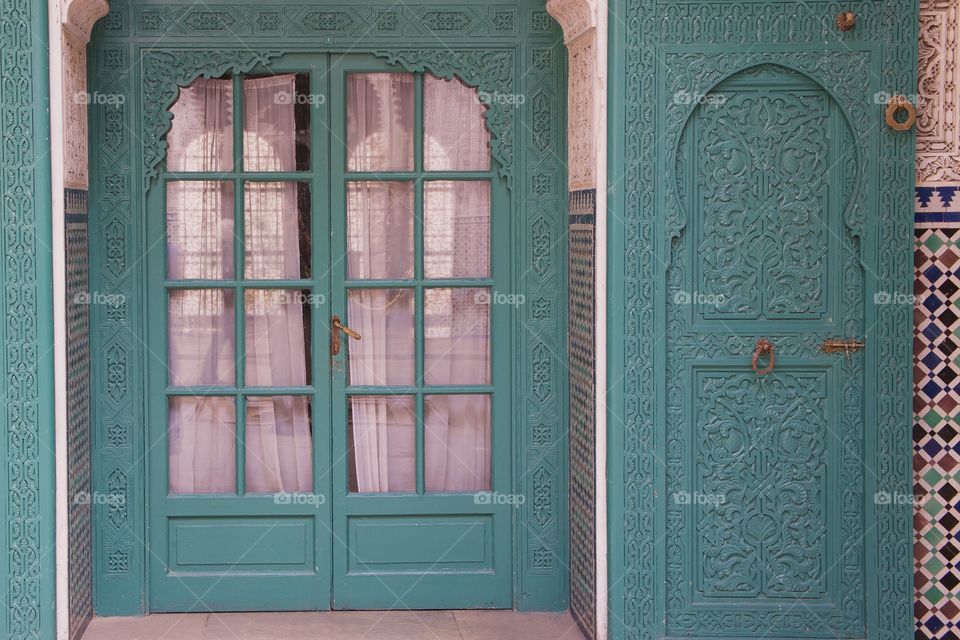 Moroccan decorative aqua wood carved doors leading from an outside court yard. In Casablanca, Morocco.
