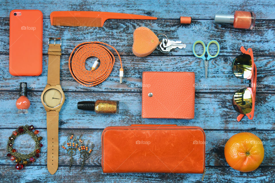 Organized orange things from women’s purse on a blue background 
