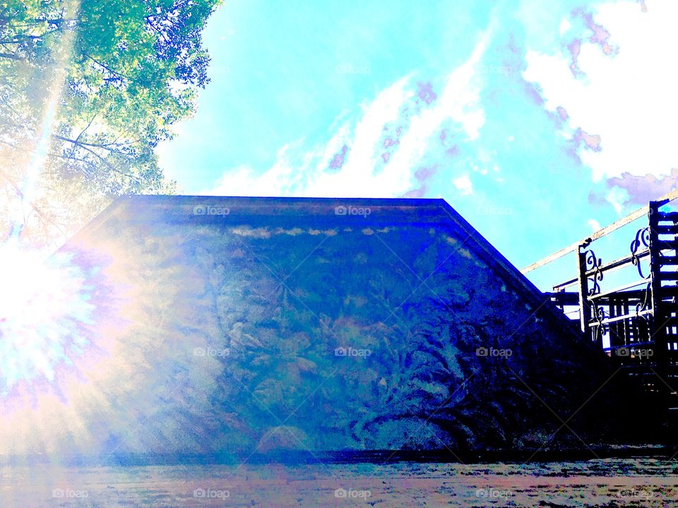 The ornamented wooden awning to a first floor window of an abandoned building on Waverly Street near Fulton in Forest Green, Brooklyn, New York. Photo was taken in the summer of 2019 looking up into the sky just as the sun cast an interesting flare.
