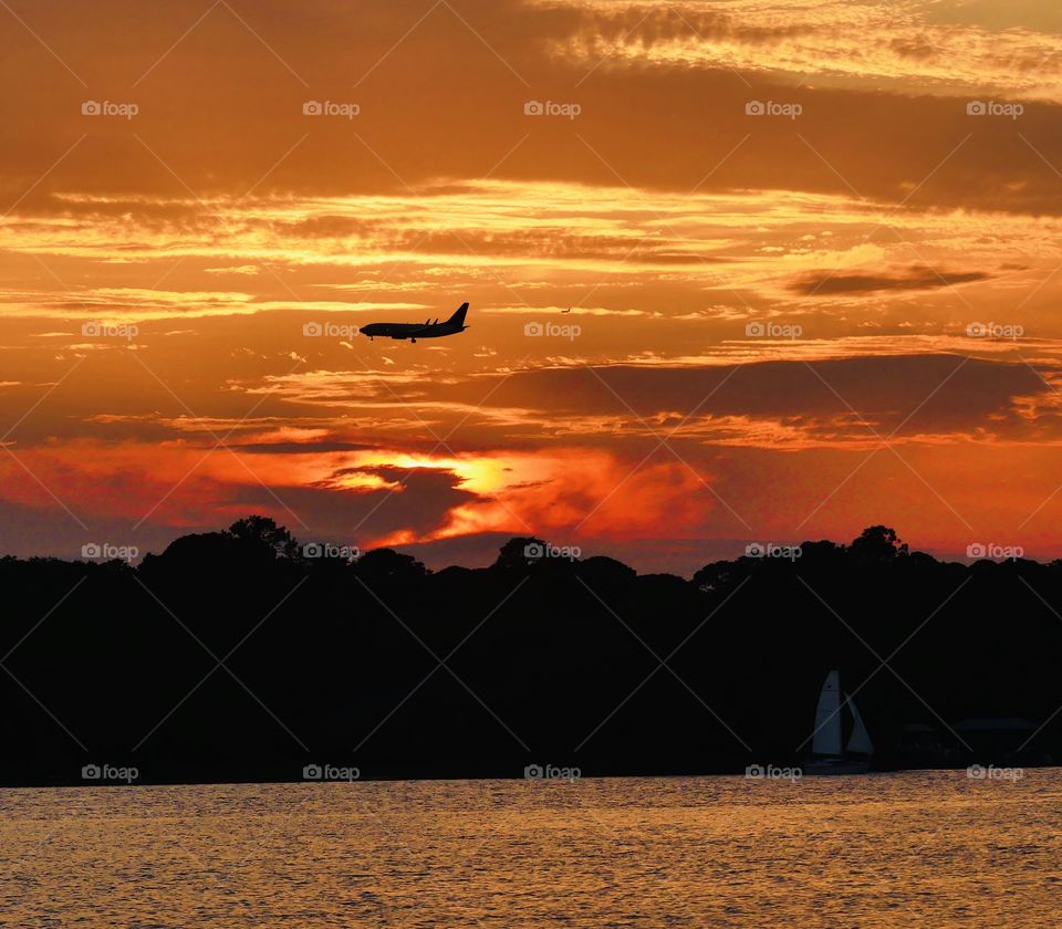 An Airliner is passing through the magnificent and colorful sunset as he prepares for his final approach to the airport 