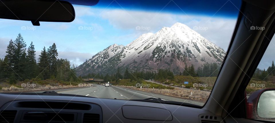 view of snow-capped Mount Shasta through car windshield on a road trip through California