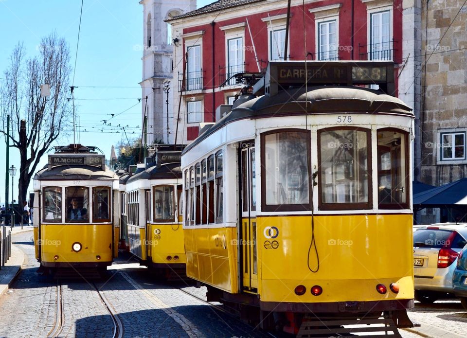 Several yellow trams in the streets of Lisbon, Portugal during the summer.