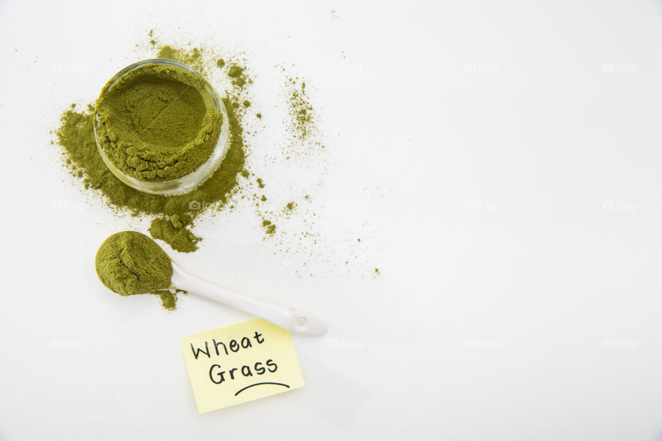 Product wheat grass powder in white bowl with white spoon on pure white background. Handwritten note with word.