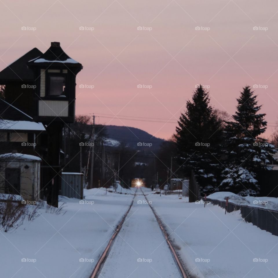 Cortland Station. Snowy tracks beside the old station in Cortland, New York, at dusk, with a train in the distance