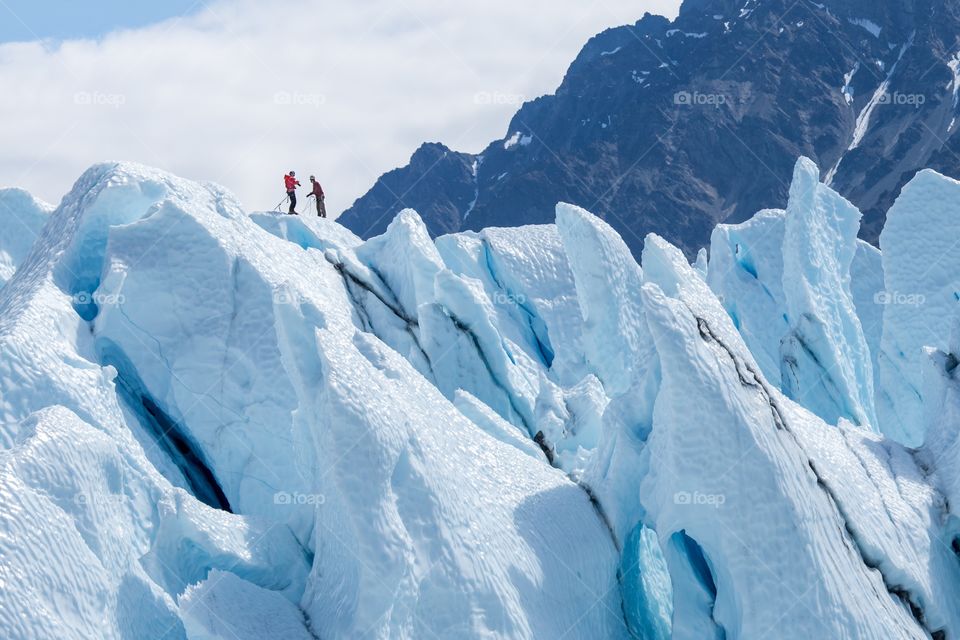 Two climbers top of glacier. Two climbers reached the top of iceberg. Challenging and hostile environment. Matanuska glacier, Alaska, USA 