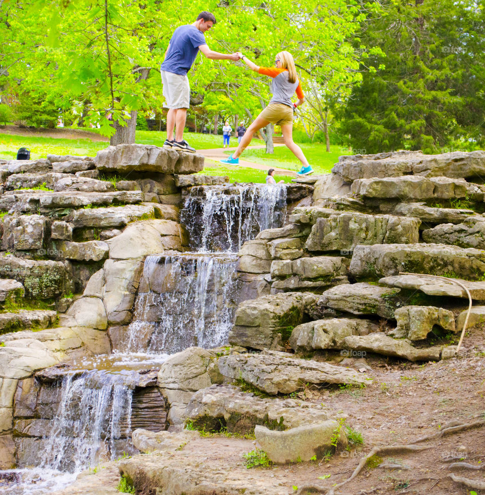 trust in love . heloping jump over waterfall 