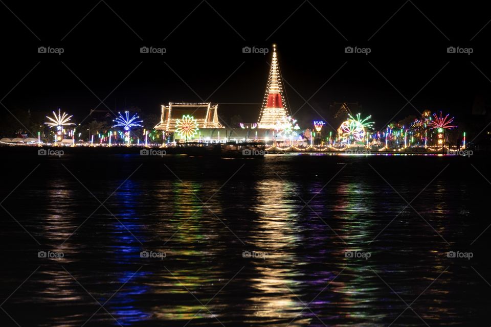 Light reflect of beautiful Thai temple fair on the river