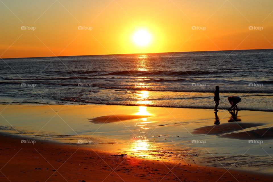 Children playing at the ocean during sunrise. 