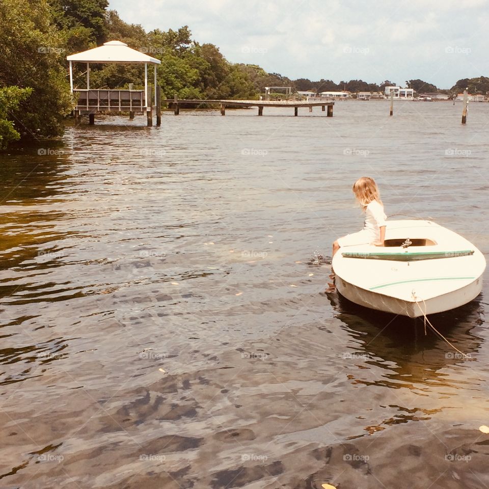 Girl on sunfish sail boat on water near mangroves 