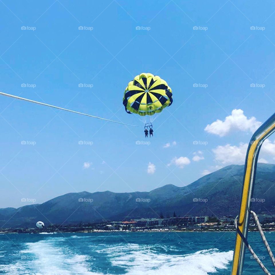 People parasailing with blue ocean and mountain backdrop 