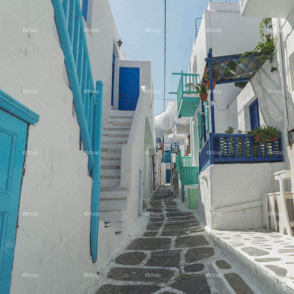 Drying white laundry on an alley corridor by traditional houses at Mykonos, Greece on a sunny day.