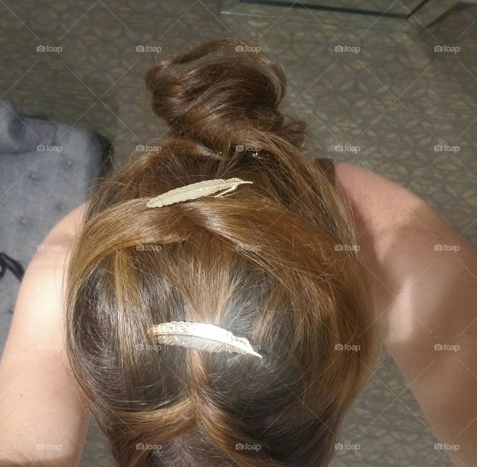 Close up shot taken from above, showing a hair style with strands of hair twisted back into a bun.