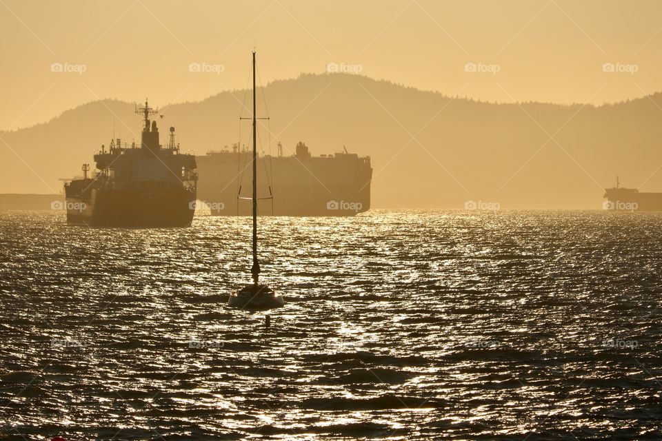 Cargo ships in harbour at sunset, smokey haze from forest fires create the golden glow