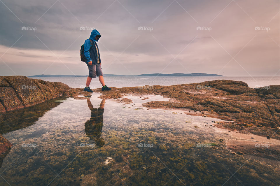 Man walking on the rocks reflected in water at Barna in Ireland