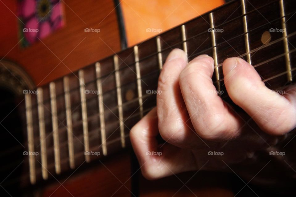 Close up of fingers playing an acoustic guitar