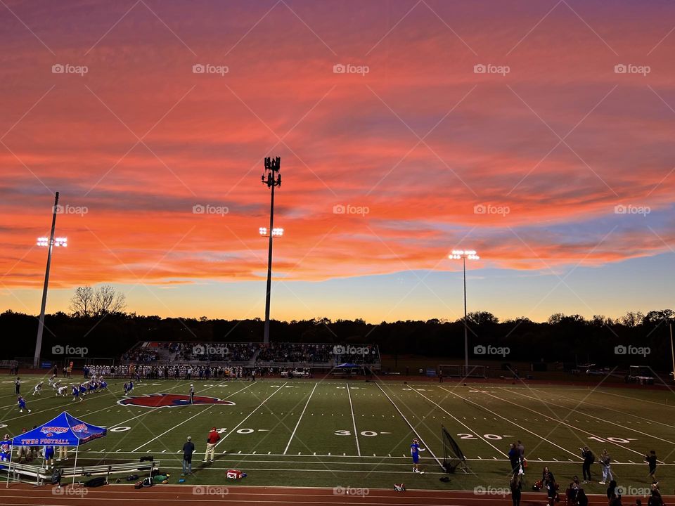 A beautiful colorful sunset at a Friday night high school football game 