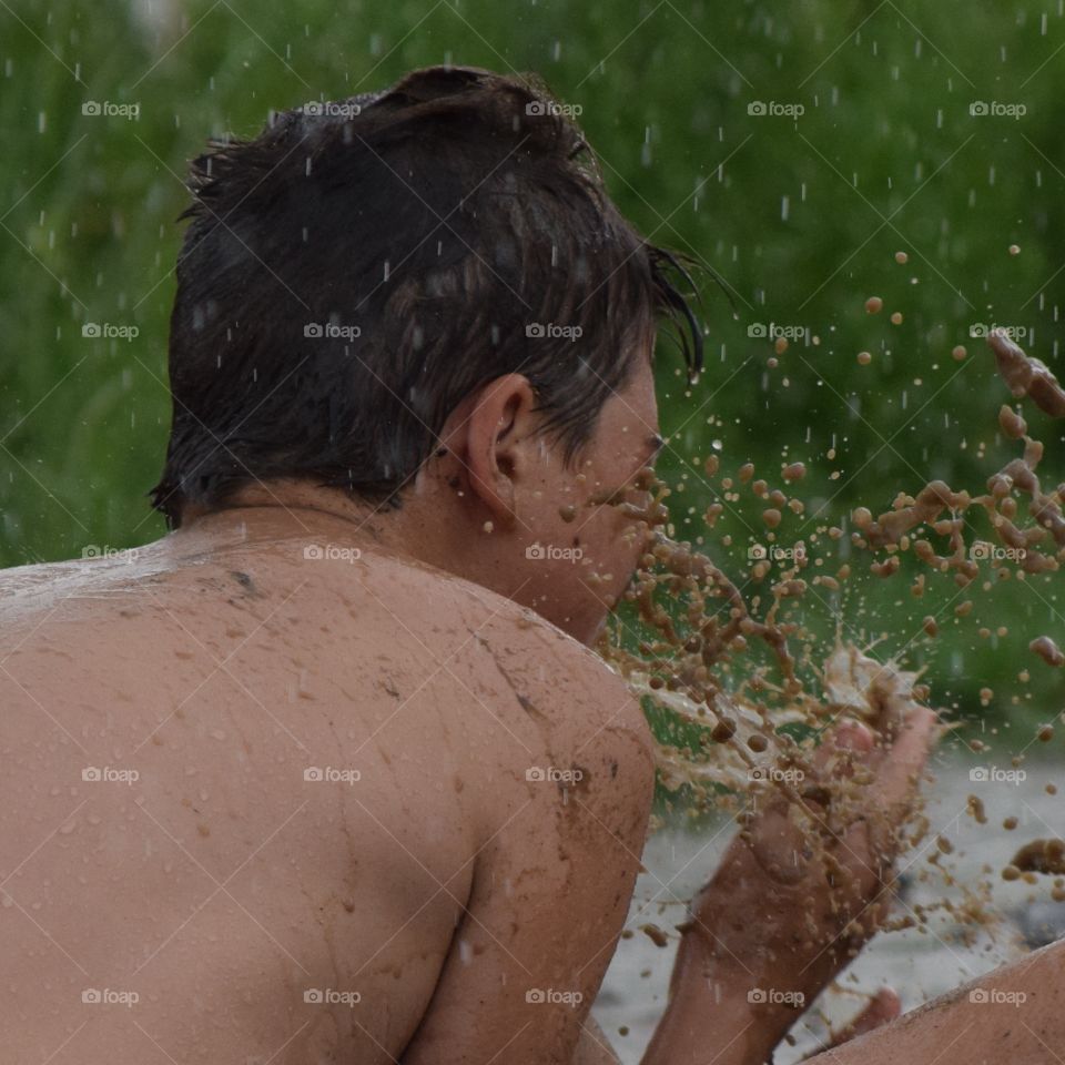 Boy playing in rain and mud