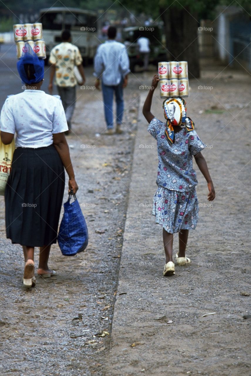 Mother and daughter walk from the market in Maputo, Mozambique with tins of Lion Lager on their head. It is not uncommon to see women carrying things on their head, but this is the first time I saw a little girl help her mother take the beer home.