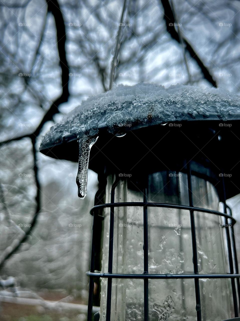 Icicle on top of a frosty bird feeder in winter time 