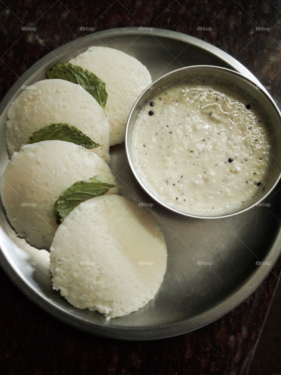 South Indian Famous Breakfast " Idli with Coconut Chutney". Idli, steamed cakes made of fermented rice and lentils. It can be served with sambar, a lentil-based vegetable curry or with coconut chutney.