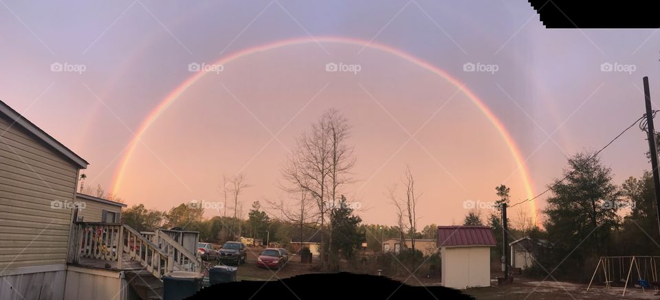 Rainbow in sky over house and cars