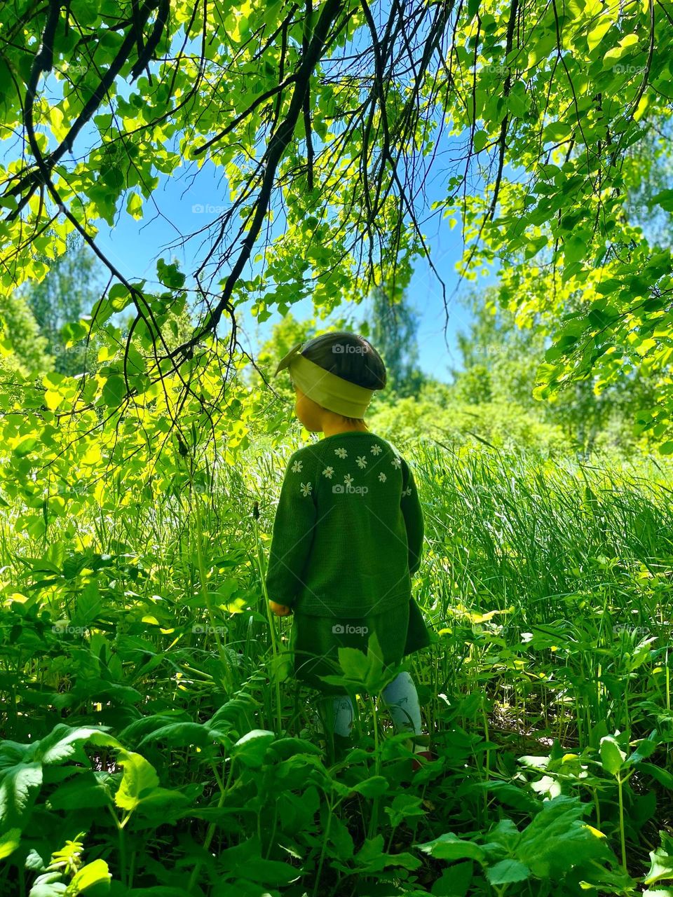 A little girl in the green clothes in nature 