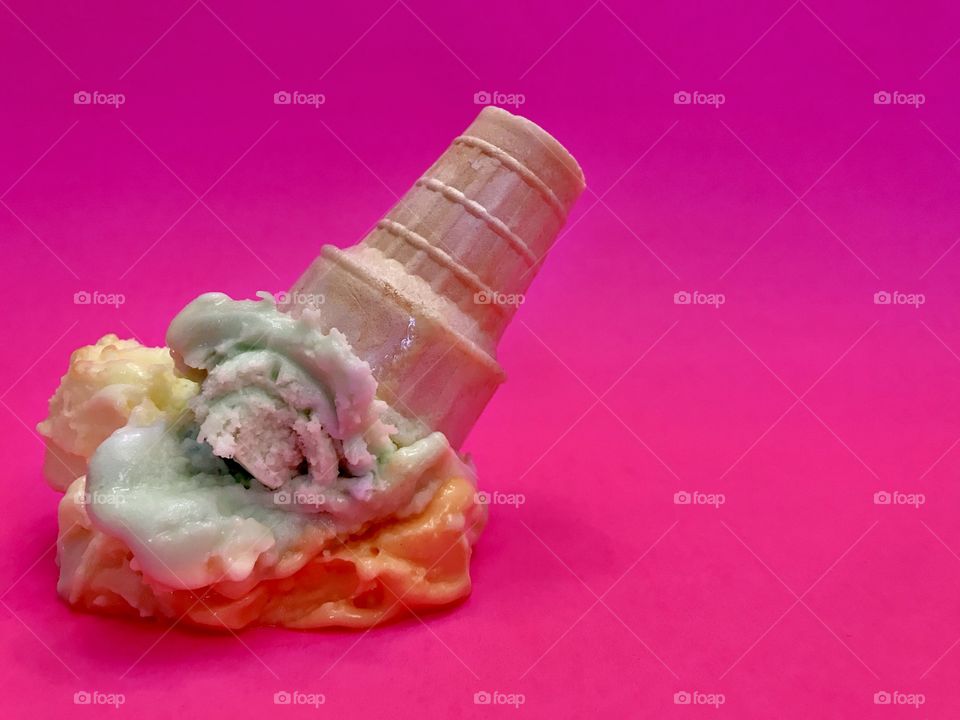 Rainbow sherbet in cone smashed on bright pink surface