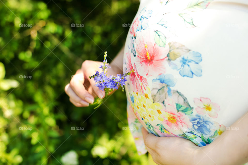 Mid section view of pregnant woman with flowers
