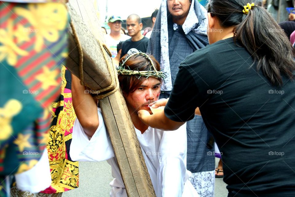 a catholic devotee is given water while reenacting the death of jesus christ on good friday during holy week in cainta, rizal, philippines, asia