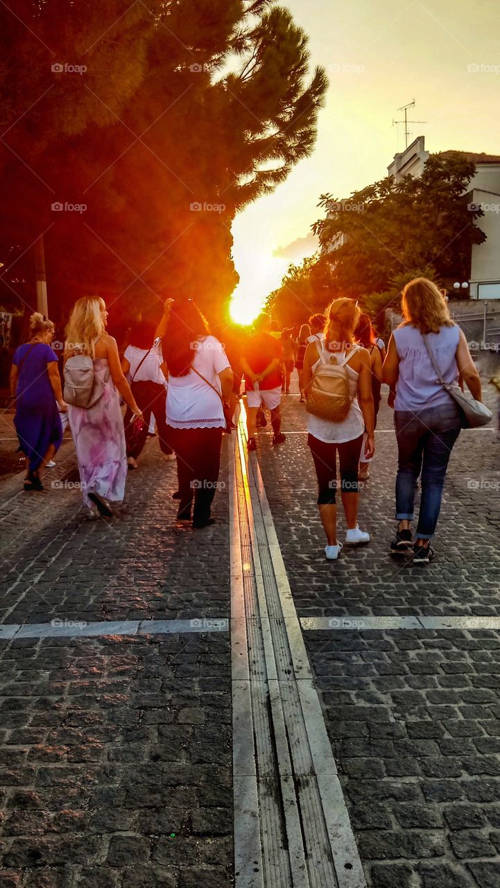 A group of people is walking towards the sunset in Athens,Greece