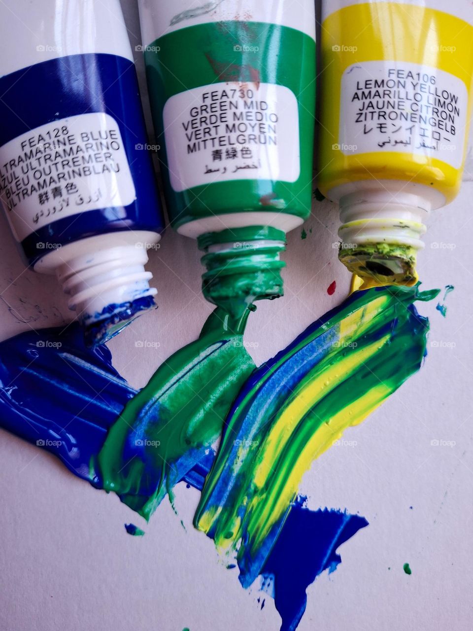 tubes of blue, green and yellow paint smeared on paper