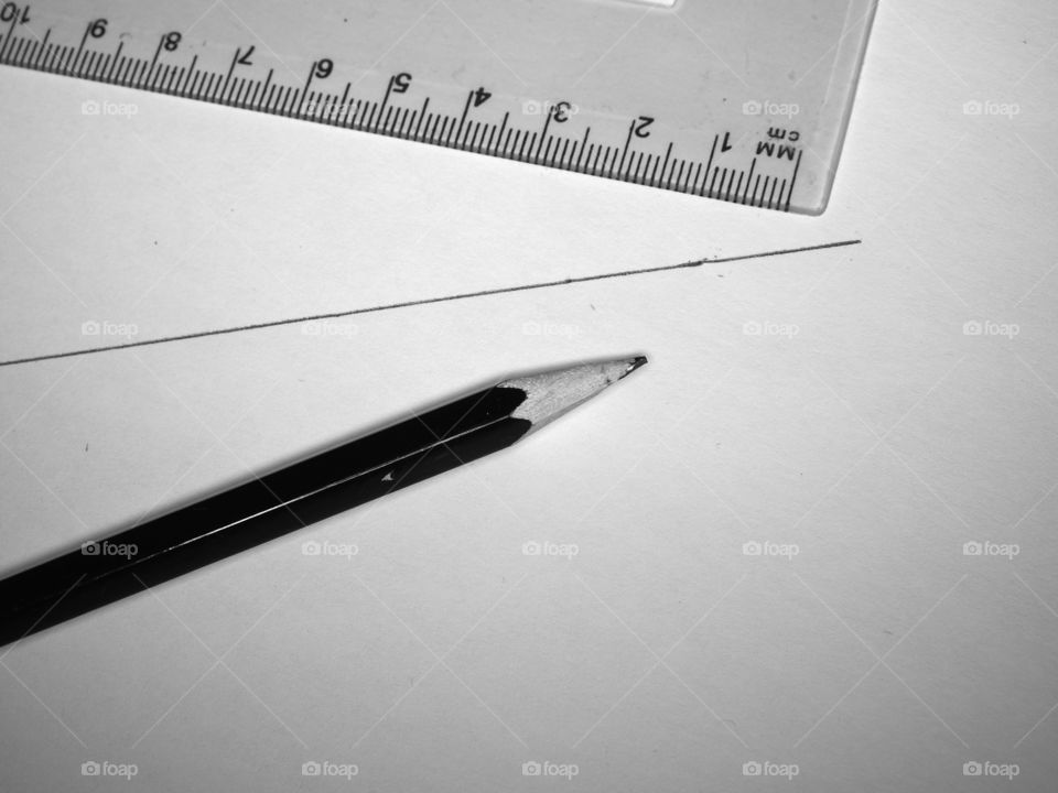 A line is drawn with a pencil on a sheet of white paper, next to it lies a pencil and a ruler.