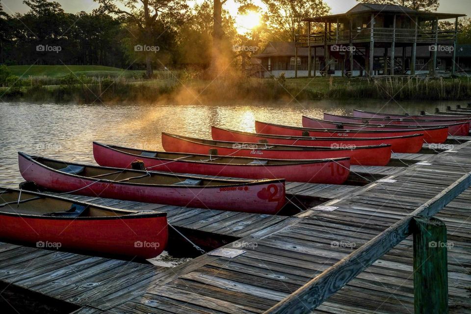 Bright red canoes wait for the kids to wake up in the stillness if the early morning. 