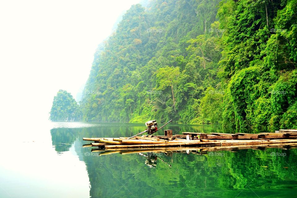 Bamboo raft and mountain with reflect on the water at Choew Lan dam