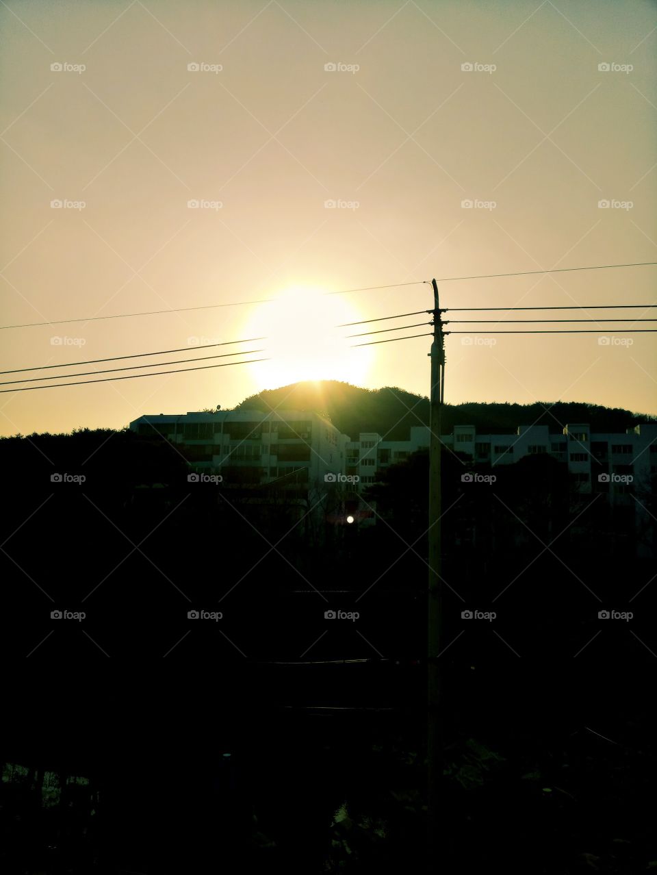 The sunset sunlight just right at the top of the mountain shining so bright that makes around you seems quite dark while watching it. Yangsan City, South Korea.