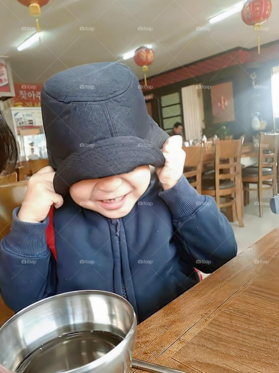 hearing someone talking nice things about him makes him feeling ashamed , so he hid his eyes in hat and smile alot.