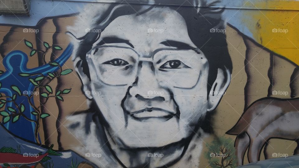 Portrait of aboriginal man in eyeglasses on a parking lot wall mural.