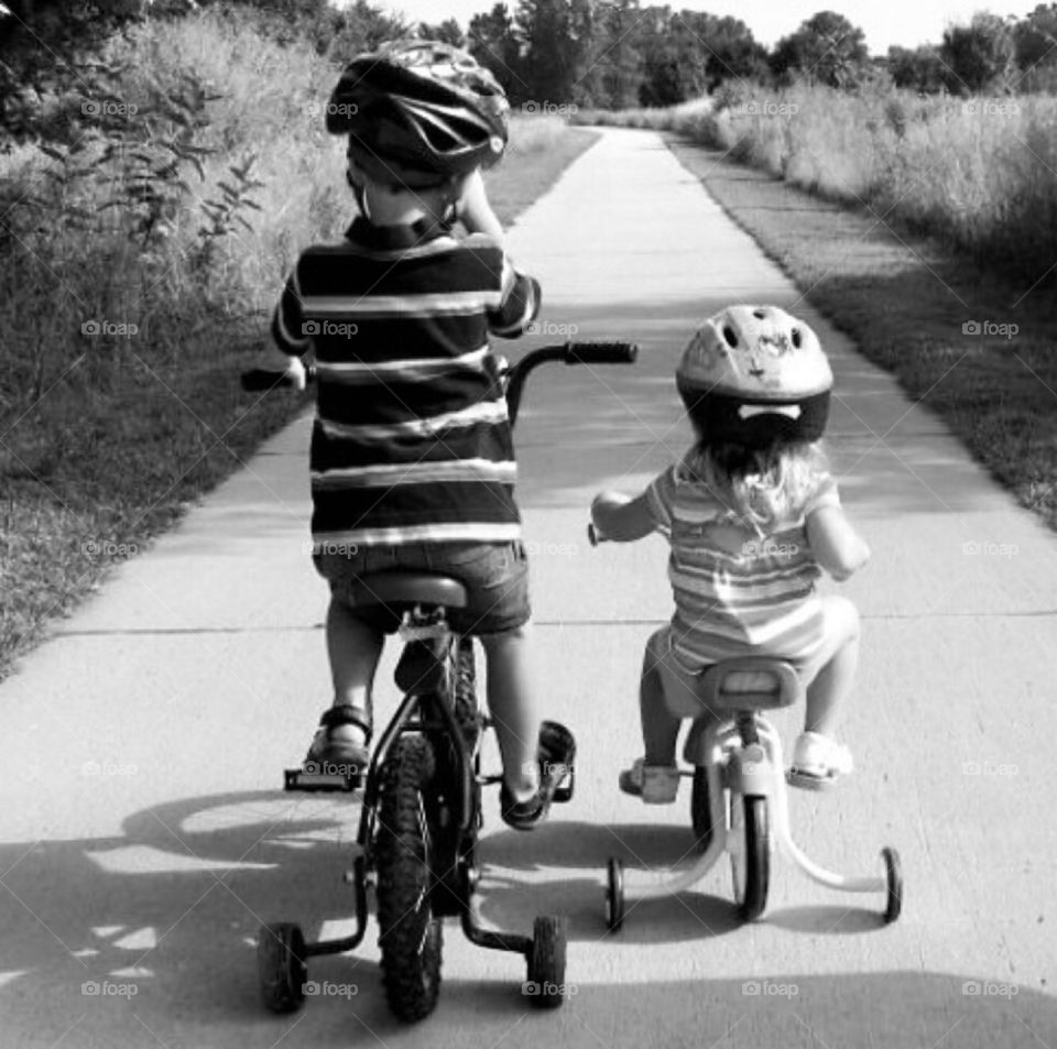 A ride on the trail. Brother and his sister enjoying a bike ride along the park trail