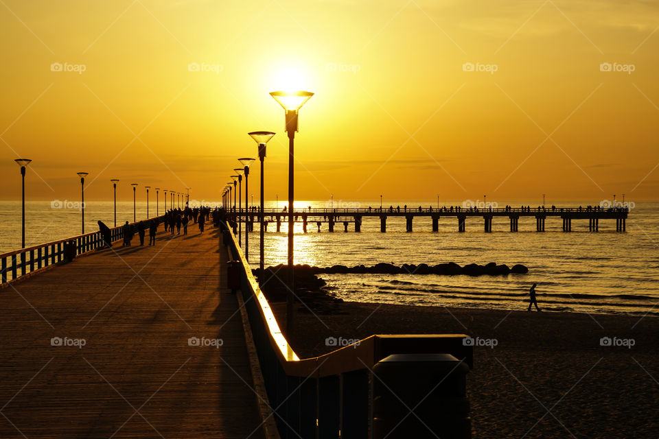 Silhouette of people walking on pier over the sea