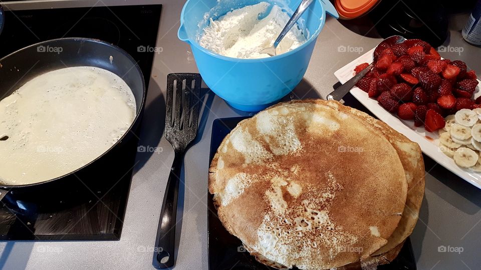 Cooking thin pancakes with whipped cream and fresh berries 