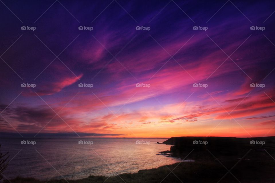 Ocean Sunset. A colourful, purple sky lighting up over the ocean from cliff tops.