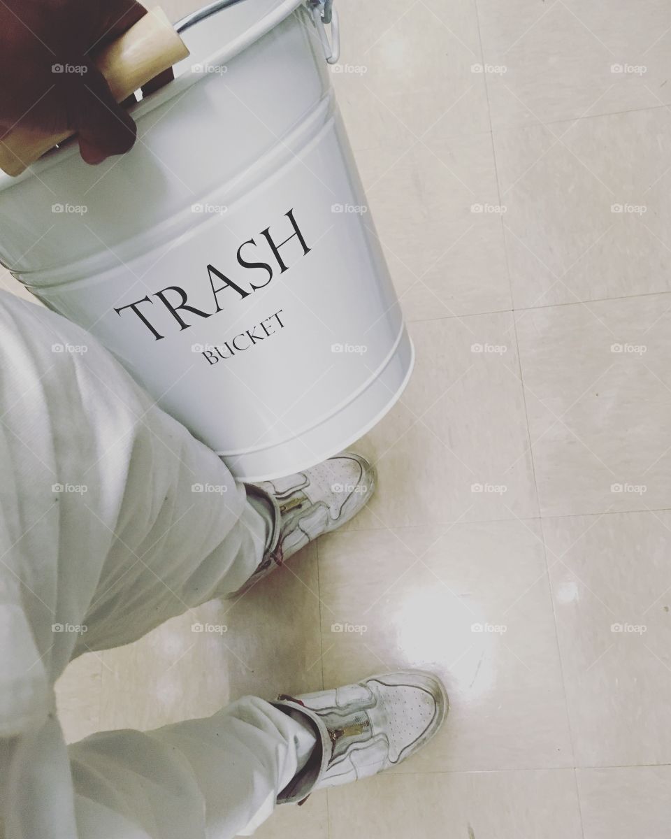 Dirty white sneakers, working white pants, and a trash bucket. 