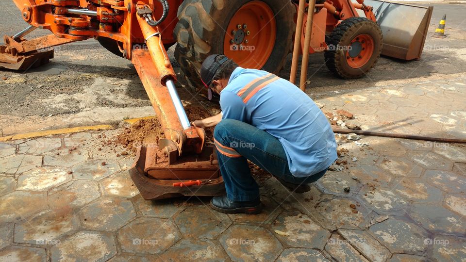 Trabalho pesado. Homem e Retro Escavadeira.