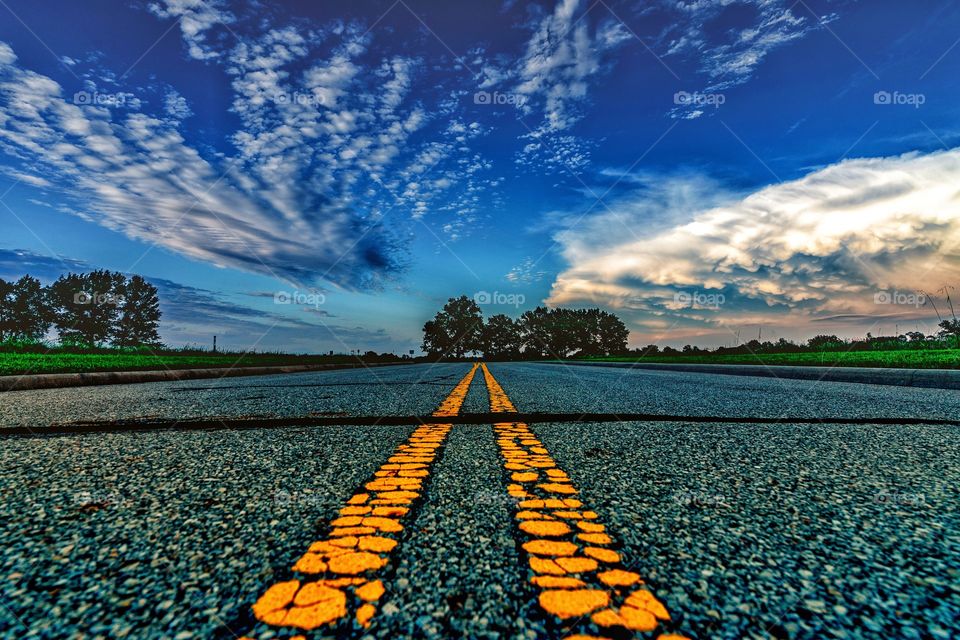 street lines leading to the trees with blue sky and clouds